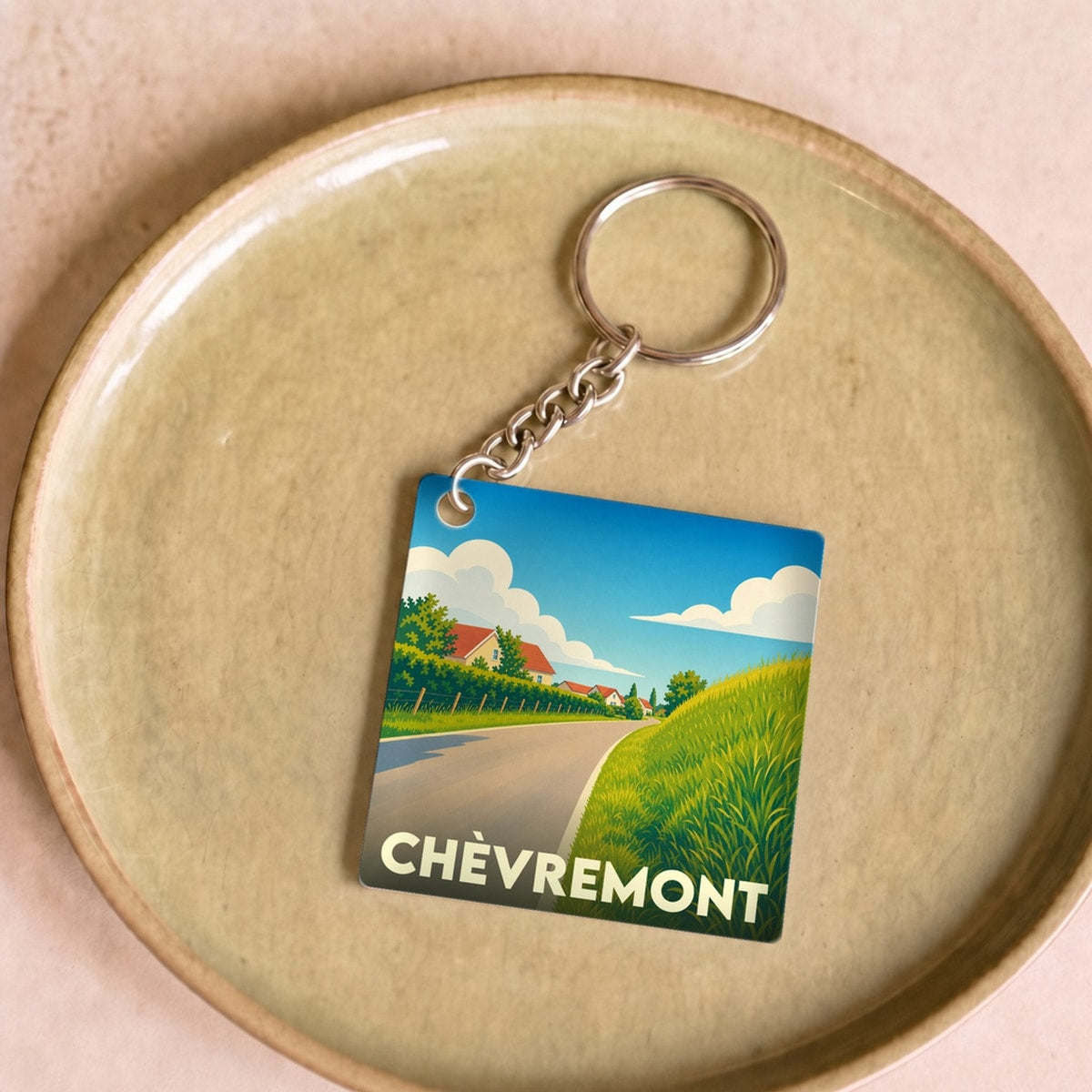 Porte-clés souvenir de la ville de Chèvremont avec une illustration stylisée de son paysage champêtre.