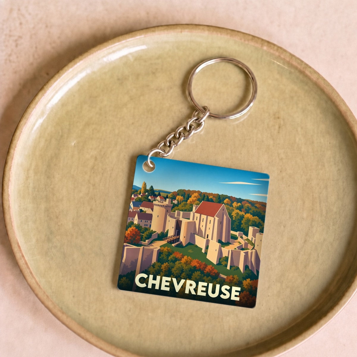 Porte-clés souvenir de la ville de Chevreuse avec une illustration stylisée du château et de la vallée.