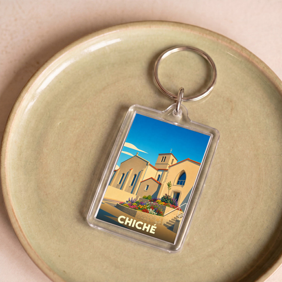 Porte-clés souvenir de la ville de Chiché avec une illustration stylisée de son église fleurie.