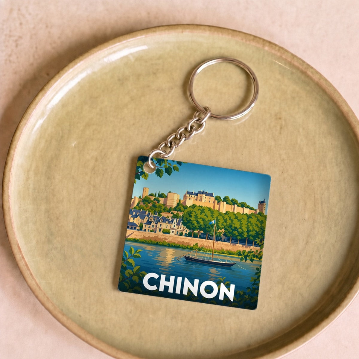 Porte-clés souvenir de la ville de Chinon avec une illustration stylisée du château et de la Vienne.