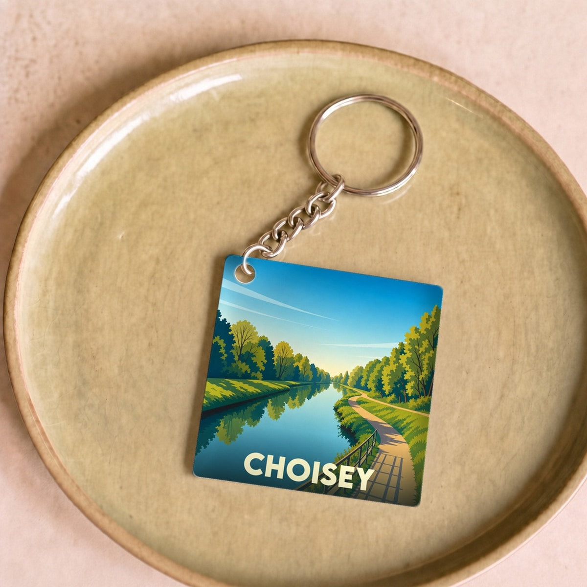 Porte-clés souvenir de la ville de Choisey avec une illustration stylisée d'un canal bordé d'arbres.