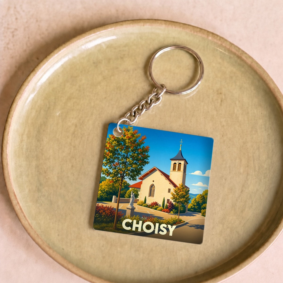 Porte-clés souvenir de la ville de Choisy avec une illustration stylisée de son église sous un ciel bleu.