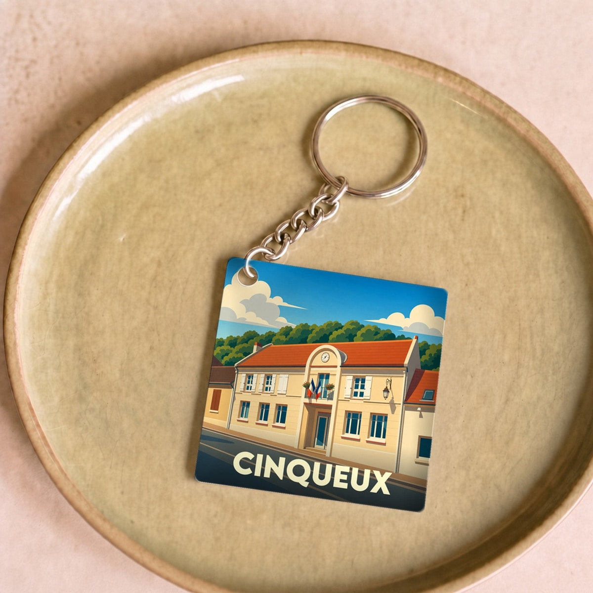 Porte-clés souvenir de la ville de Cinqueux avec une illustration stylisée de sa mairie.