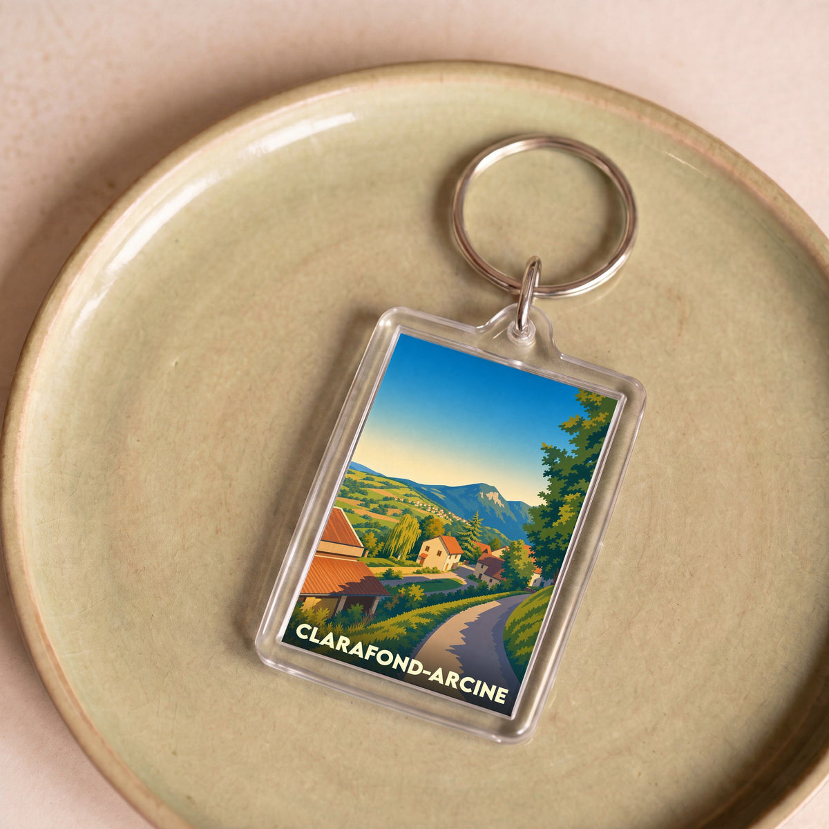 Porte-clés souvenir de la commune de Clarafond-Arcine avec une illustration de paysage stylisée.