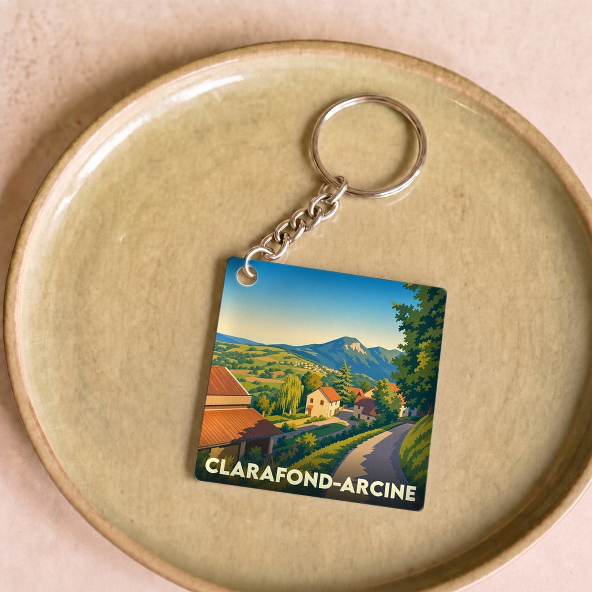Porte-clés souvenir de la commune de Clarafond-Arcine avec une illustration de paysage stylisée.