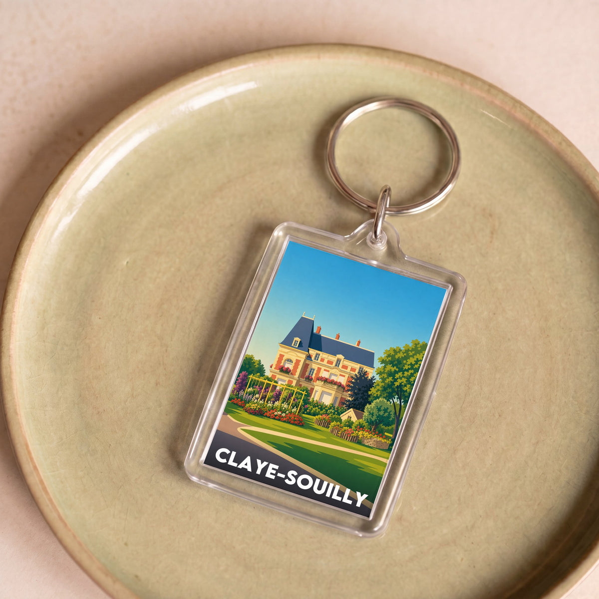 Porte-clés souvenir de la ville de Claye-Souilly avec une illustration stylisée d'une demeure et de ses jardins.