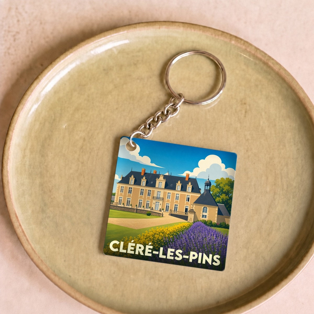 Porte-clés souvenir de la ville de Cléré-les-Pins avec une illustration stylisée de son château.