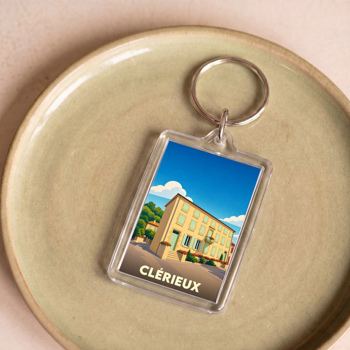 Porte-clés souvenir de la ville de Clérieux avec une illustration stylisée d'une bâtisse traditionnelle.