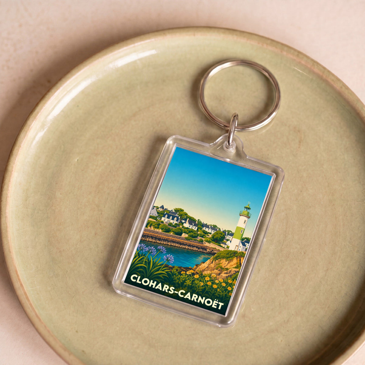Porte-clés souvenir de la ville de Clohars-Carnoët avec une illustration stylisée de son littoral et de son phare.