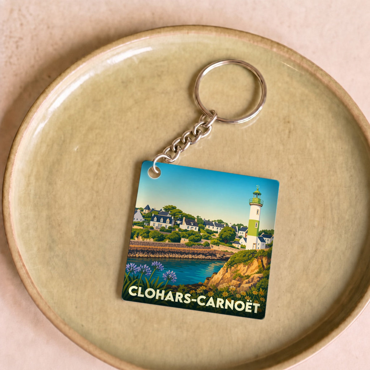 Porte-clés souvenir de la ville de Clohars-Carnoët avec une illustration stylisée de son littoral et de son phare.