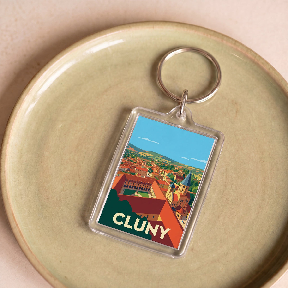 Porte-clés souvenir de la ville de Cluny avec une illustration panoramique stylisée.