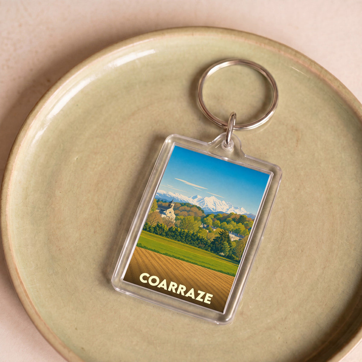 Porte-clés souvenir de la ville de Coarraze avec une illustration stylisée des Pyrénées.