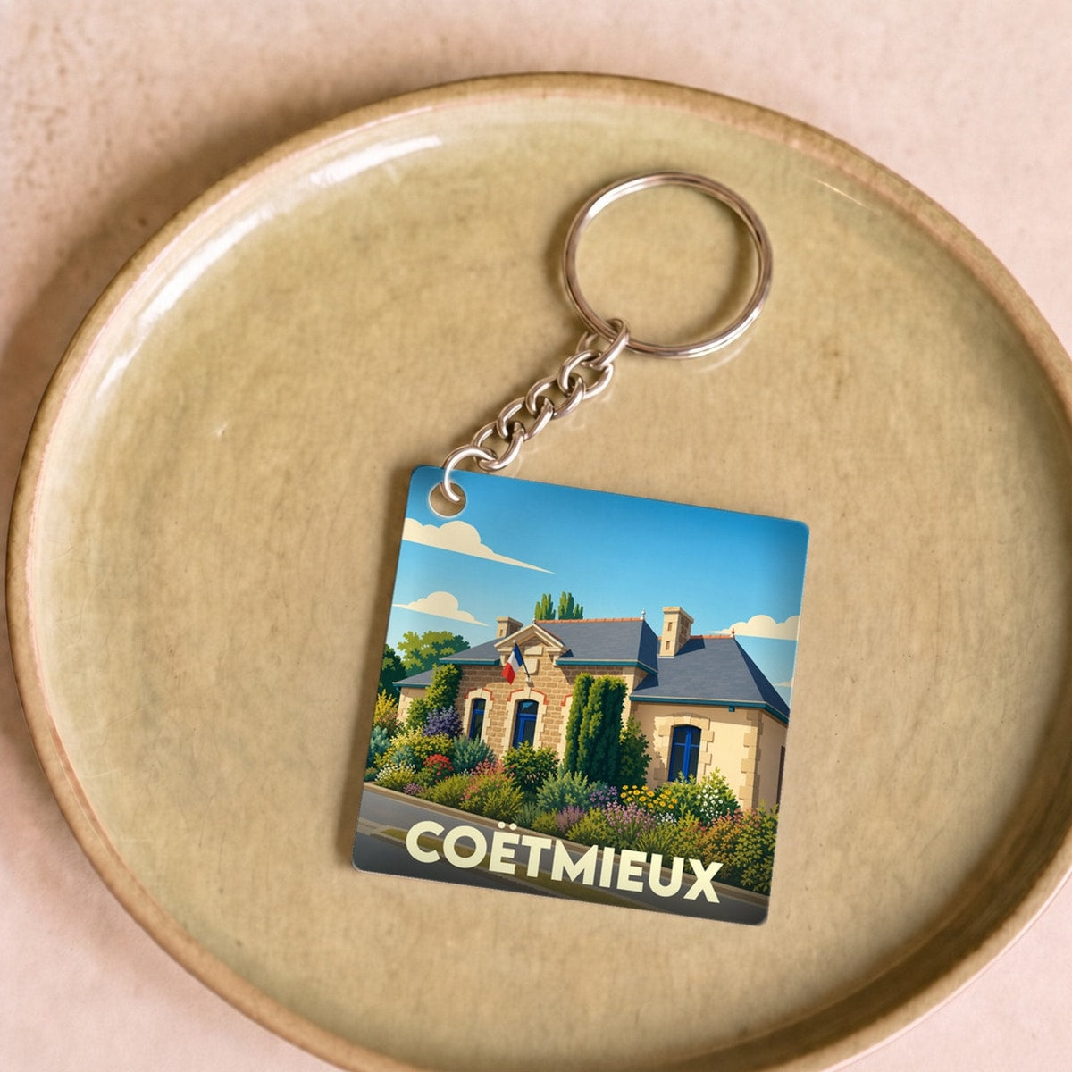 Porte-clés souvenir de la ville de Coëtmieux avec une illustration stylisée de sa mairie.