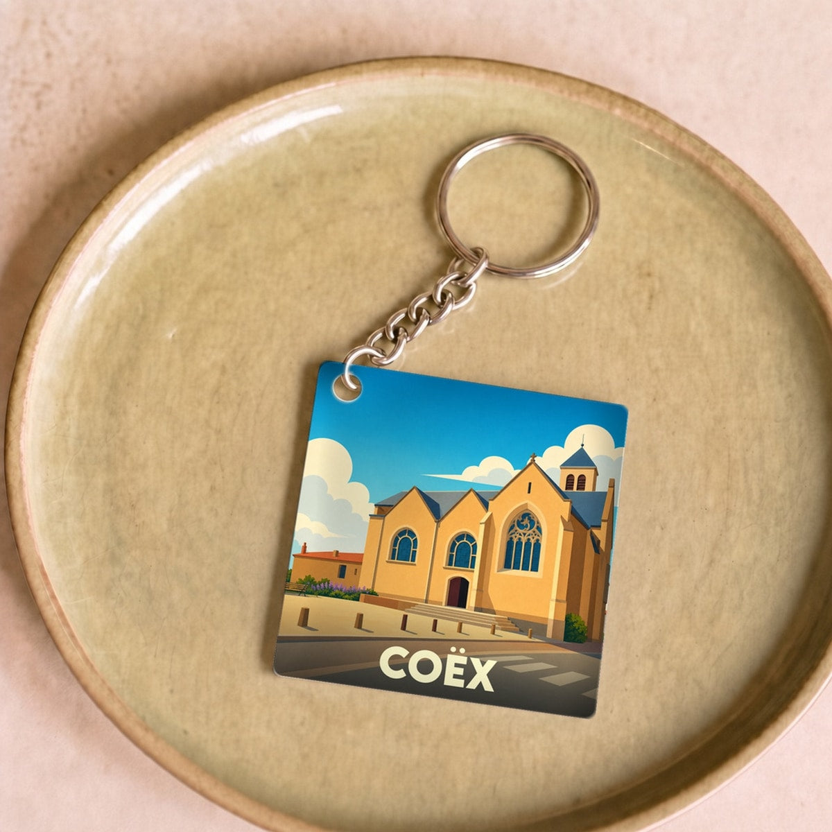 Porte-clés souvenir de la ville de Coëx avec une illustration stylisée de son église.
