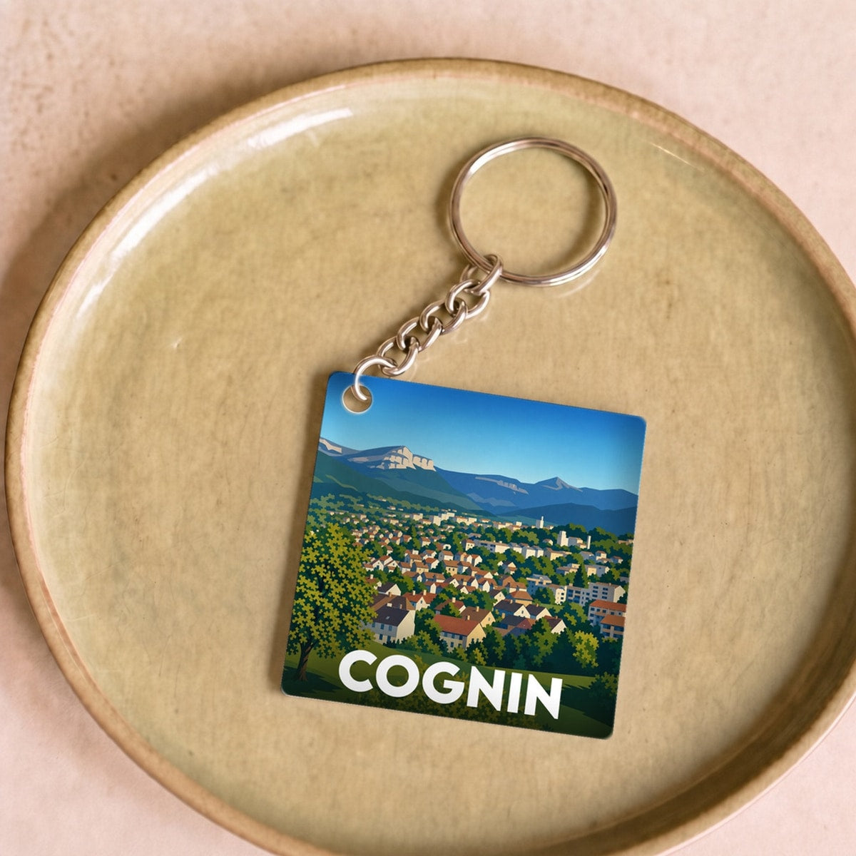 Porte-clés souvenir de la ville de Cognin avec une illustration stylisée de son paysage.