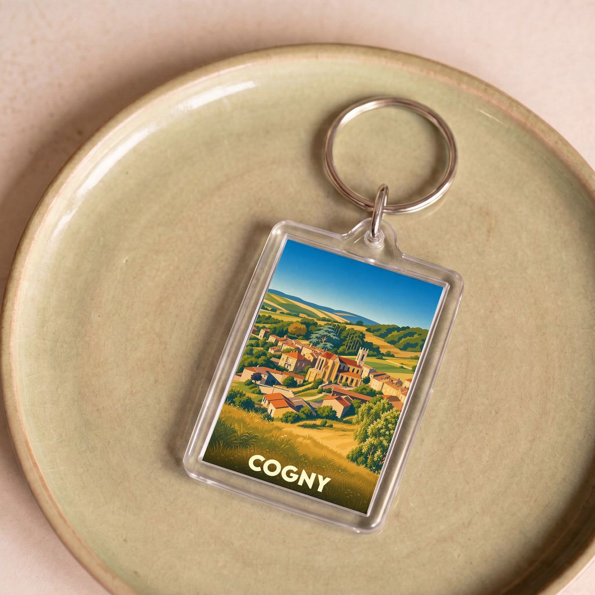 Porte-clés souvenir de la ville de Cogny avec une illustration stylisée de ses paysages et de son église.