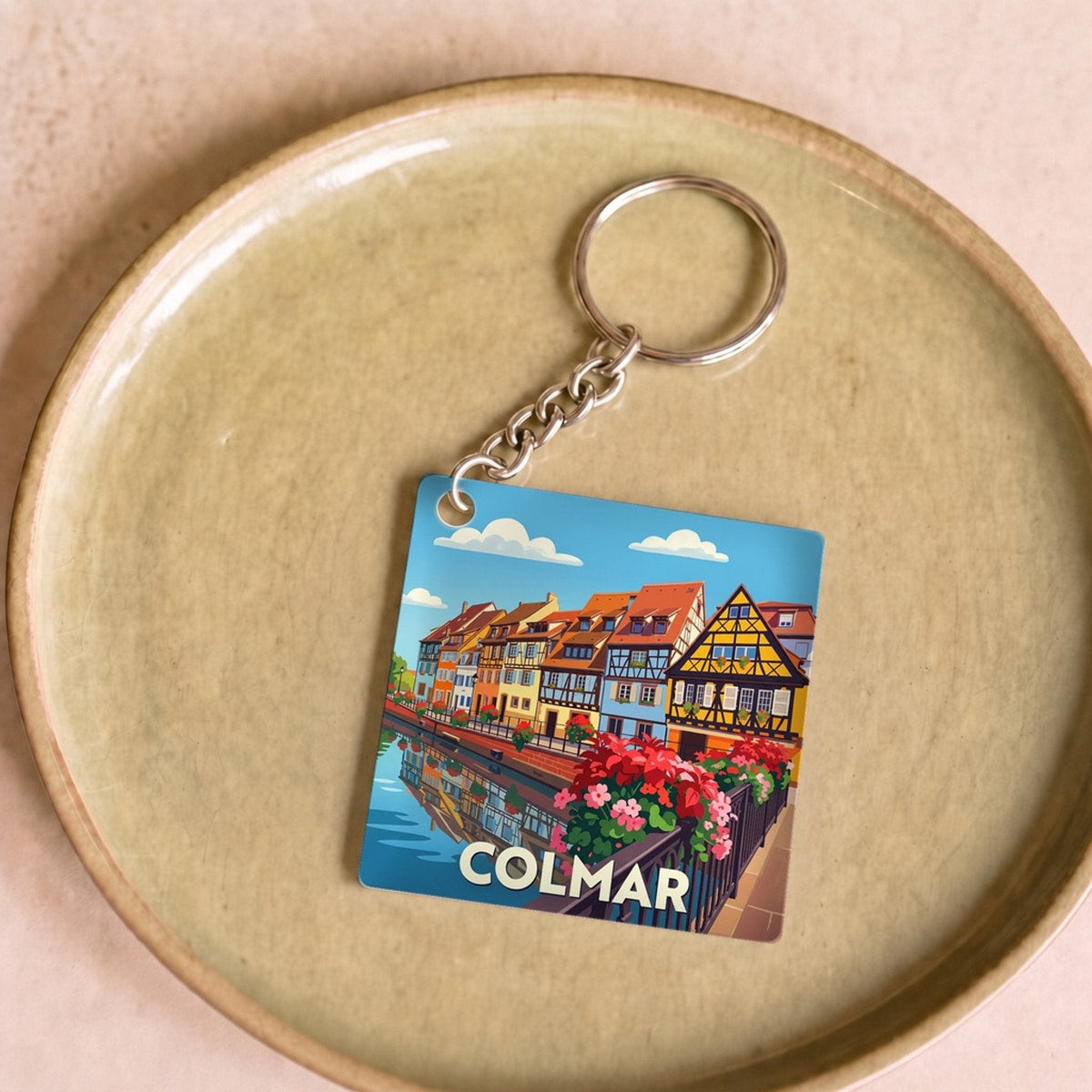 Porte-clés souvenir de la ville de Colmar avec une illustration stylisée de maisons à colombages.