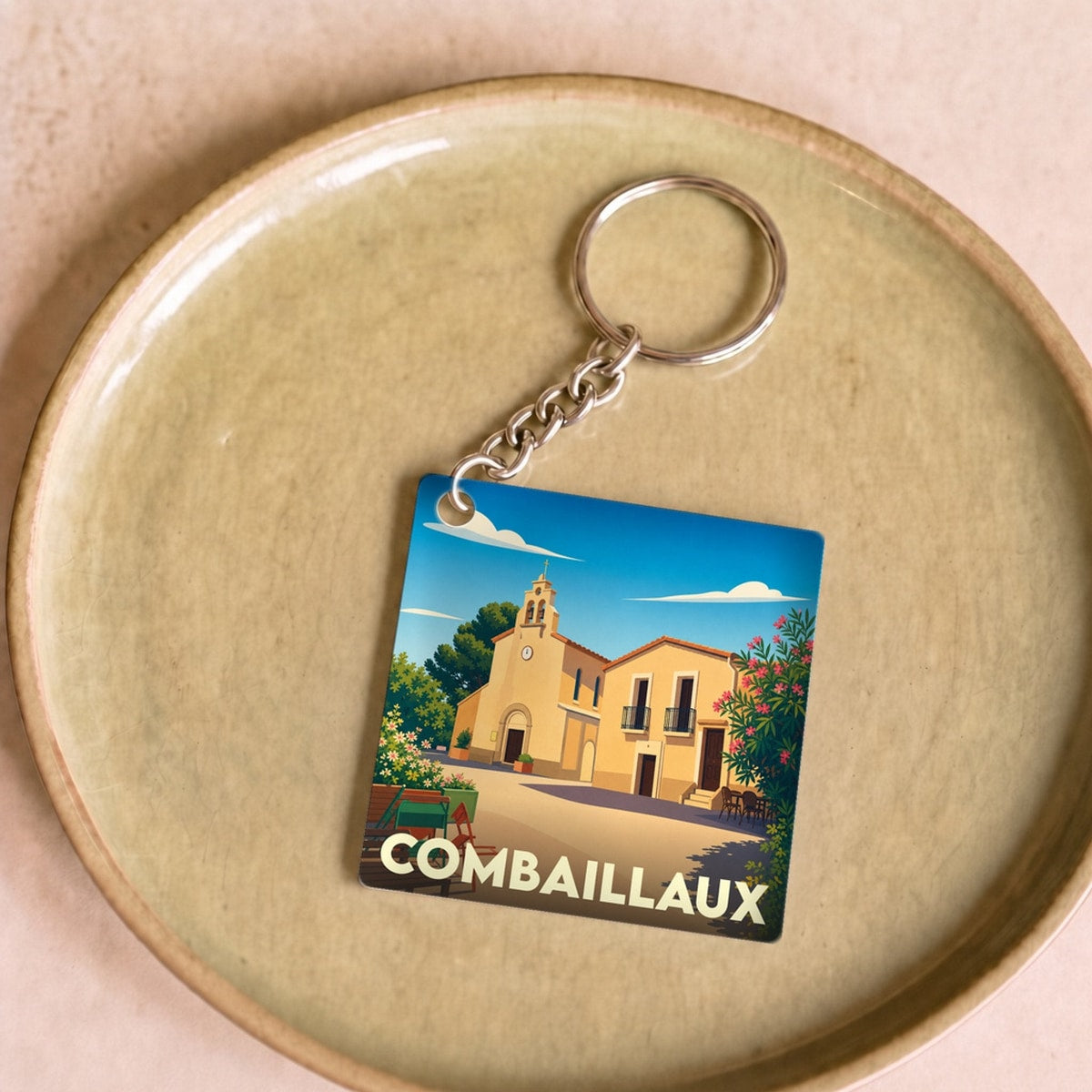 Porte-clés souvenir de la ville de Combaillaux avec une illustration stylisée.