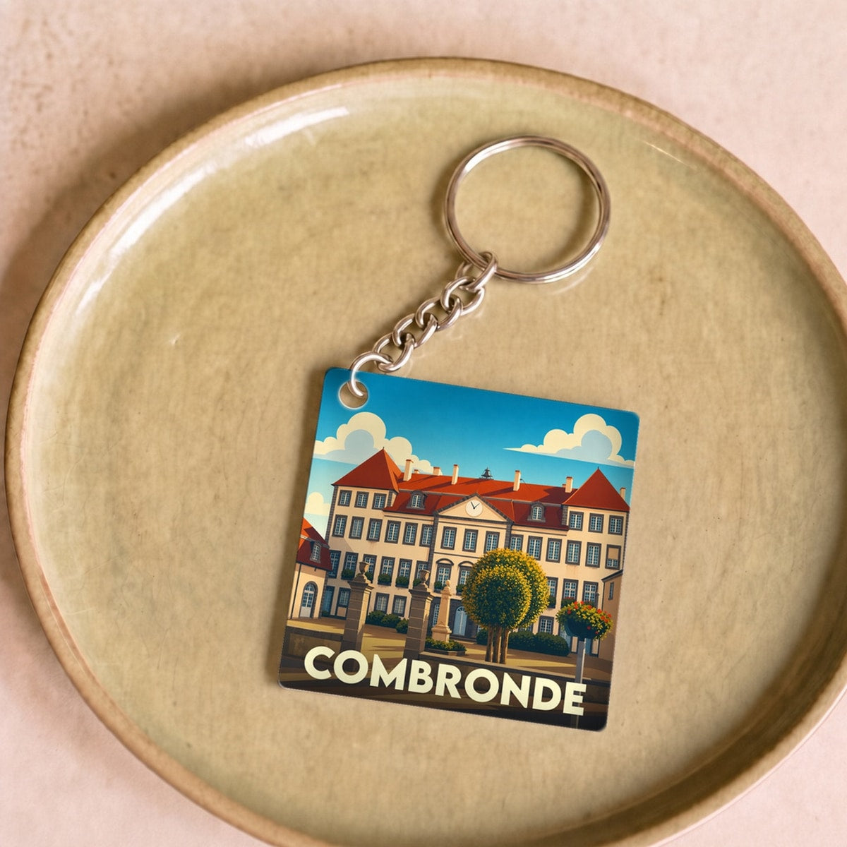 Porte-clés souvenir de la ville de Combronde avec une illustration stylisée.