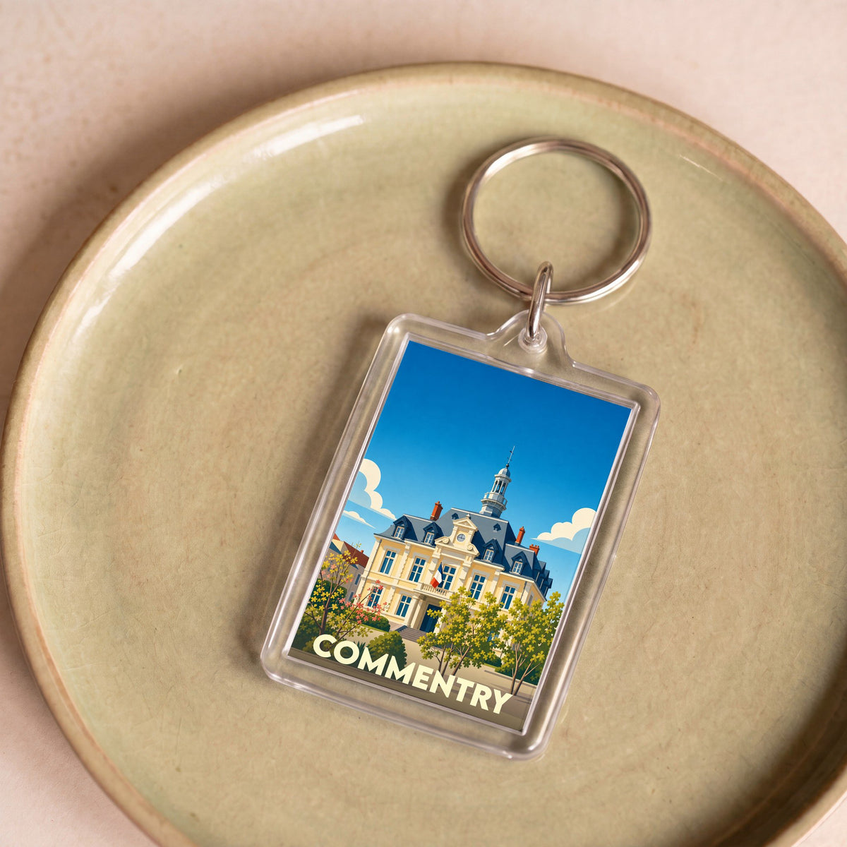 Porte-clés souvenir de la ville de Commentry avec une illustration stylisée de l'hôtel de ville.