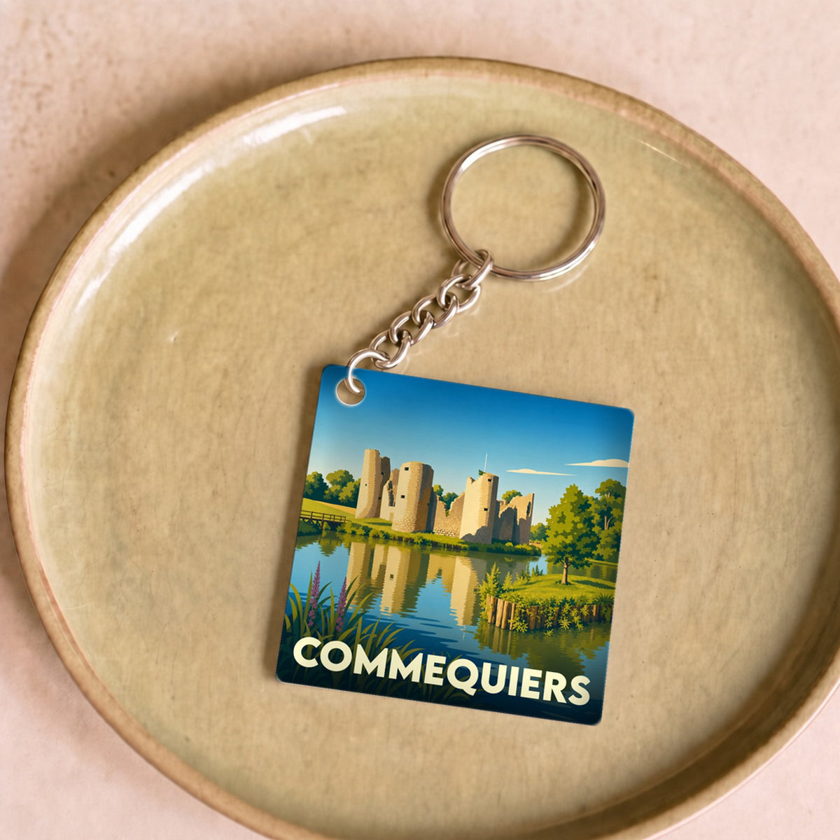 Porte-clés souvenir de la ville de Commequiers avec une illustration stylisée de son château médiéval.