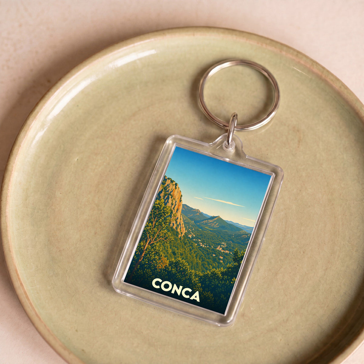 Porte-clés souvenir de la ville de Conca avec une illustration stylisée d'un paysage montagneux.