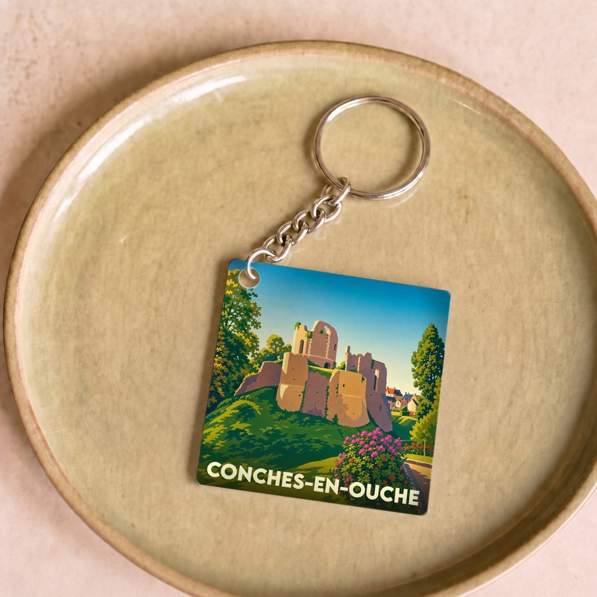 Porte-clés souvenir de la ville de Conches-en-Ouche avec une illustration stylisée de son château.