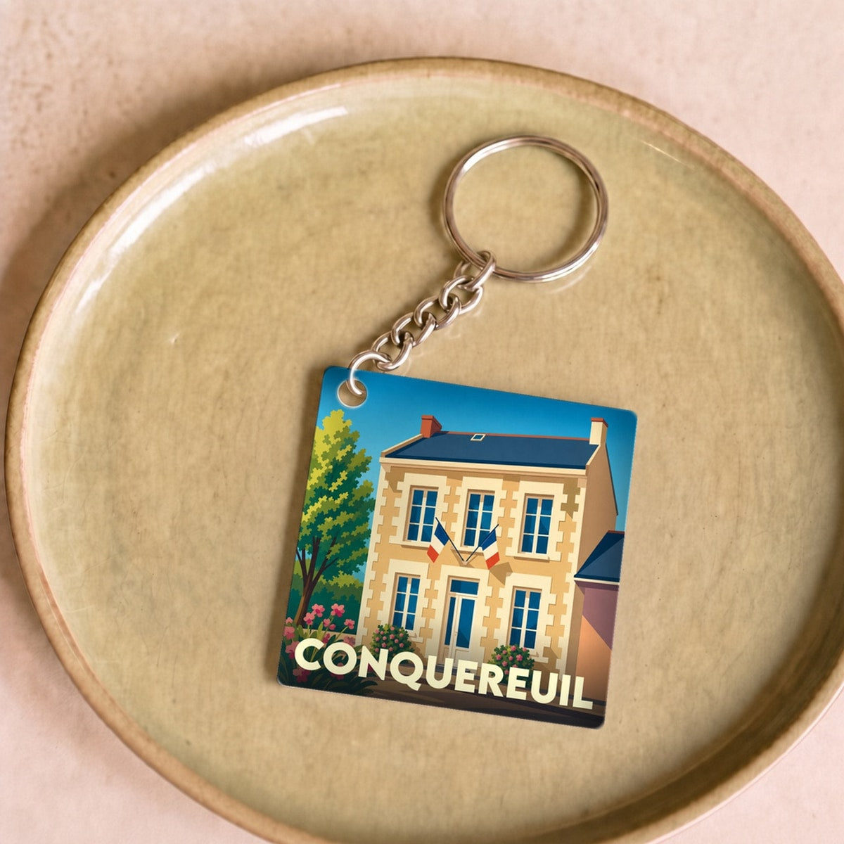 Porte-clés souvenir de la ville de Conquereuil avec une illustration stylisée.