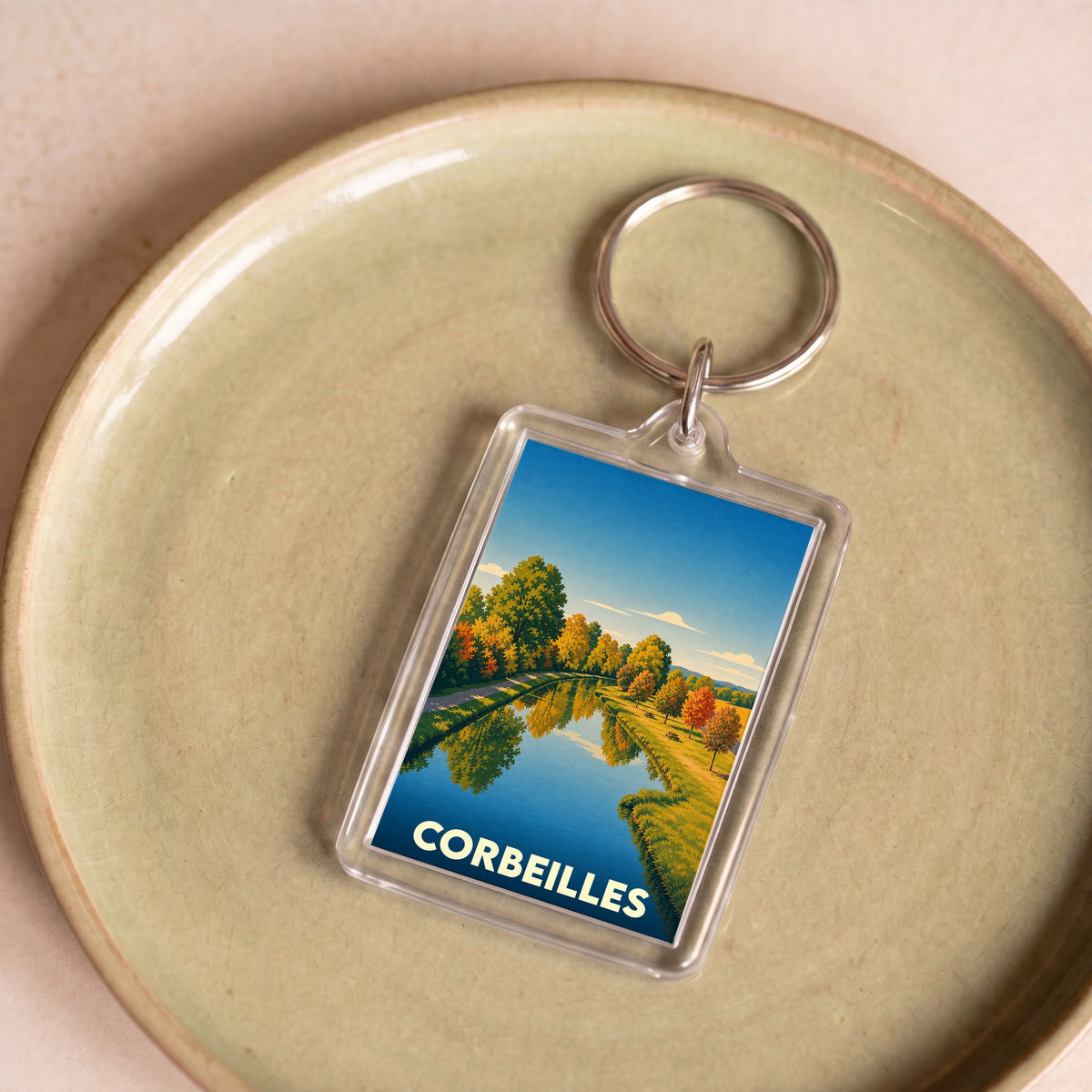 Porte-clés souvenir de la ville de Corbeilles avec une illustration stylisée d'un canal bordé d'arbres.
