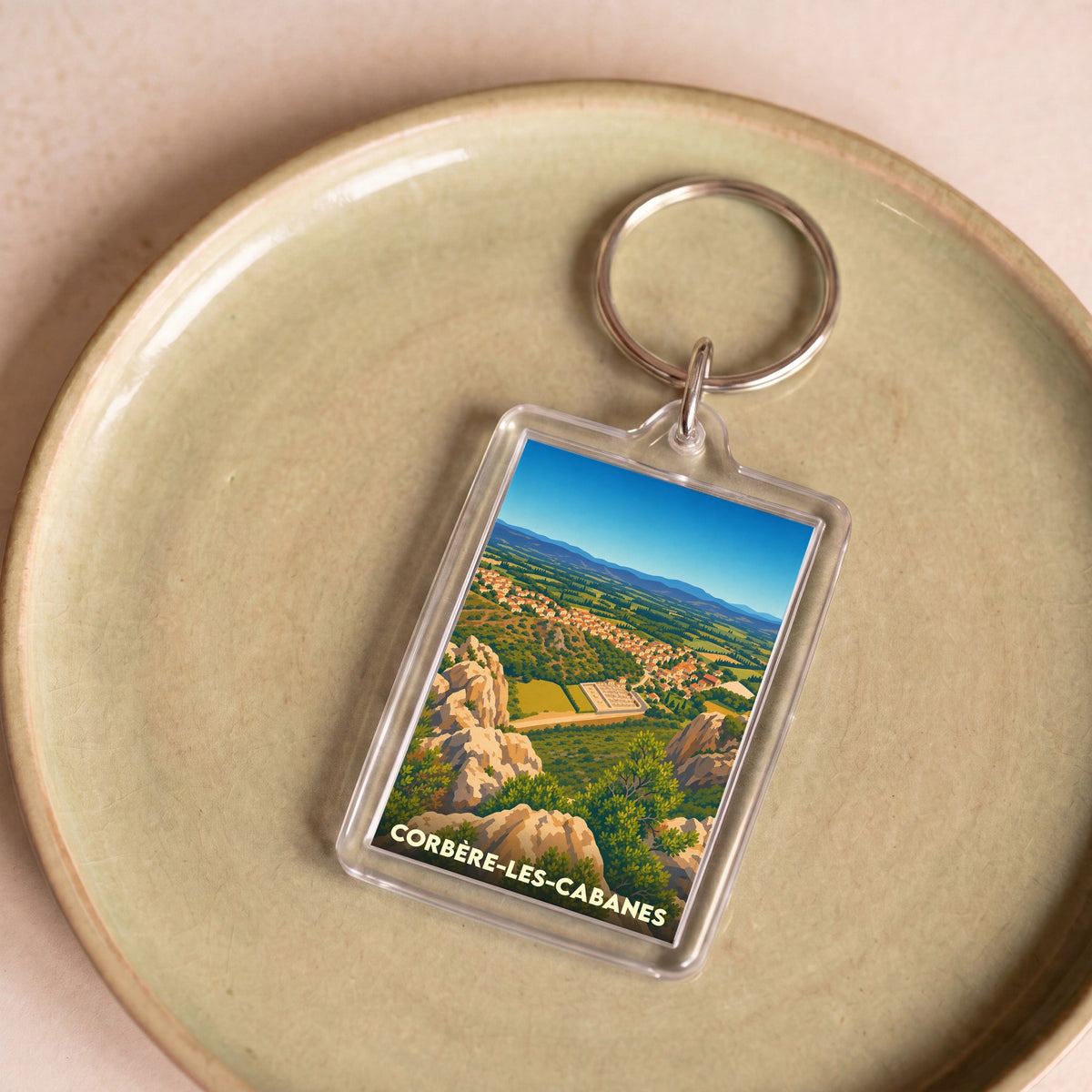 Porte-clés souvenir de la ville de Corbère-les-Cabanes avec une illustration stylisée de son paysage.
