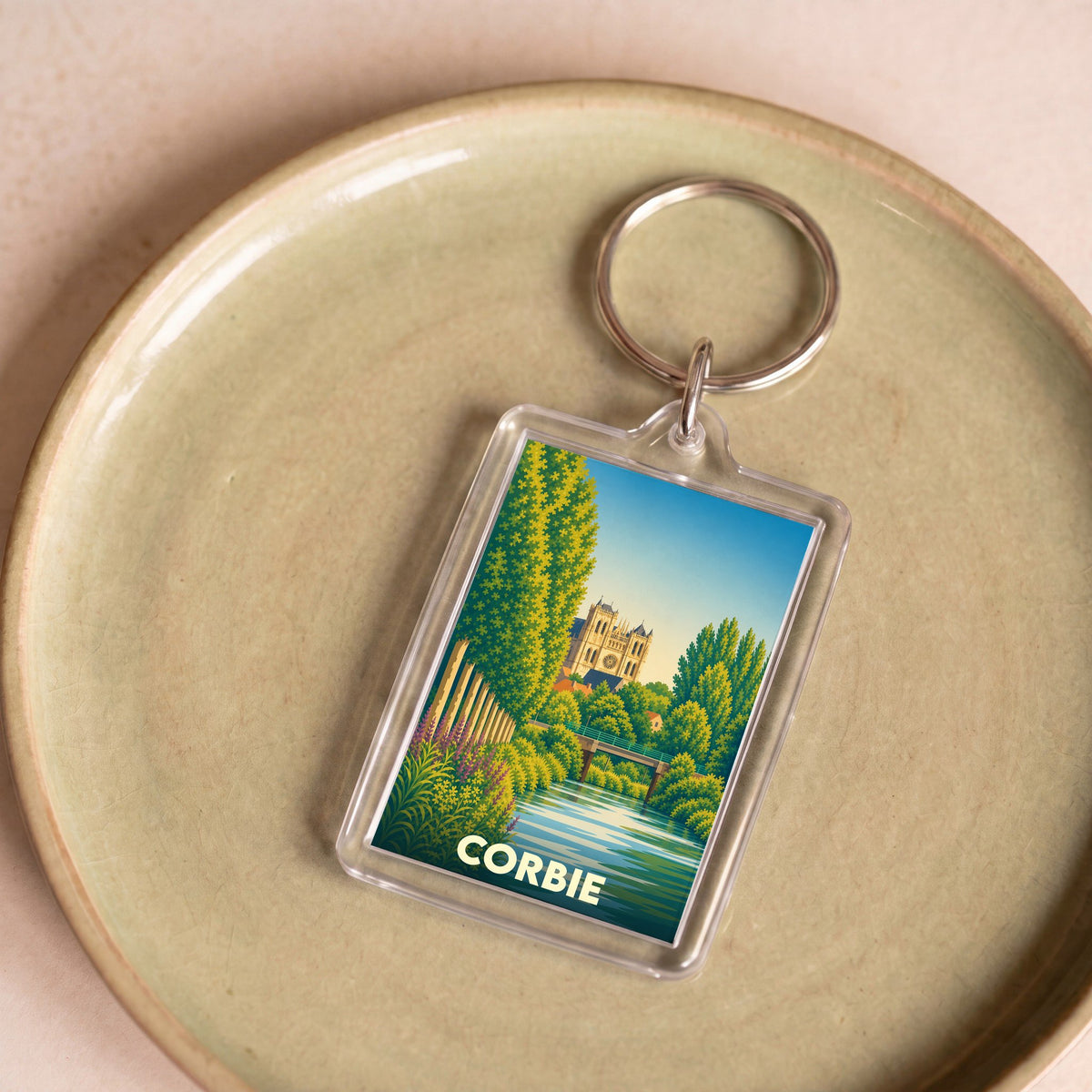 Porte-clés souvenir de la ville de Corbie avec une illustration stylisée de son abbaye et de la Somme.