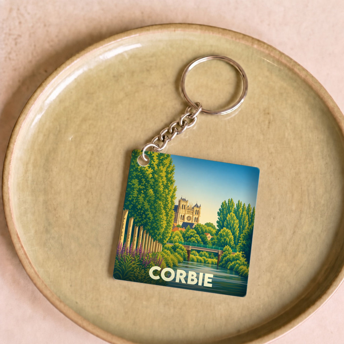 Porte-clés souvenir de la ville de Corbie avec une illustration stylisée de son abbaye et de la Somme.
