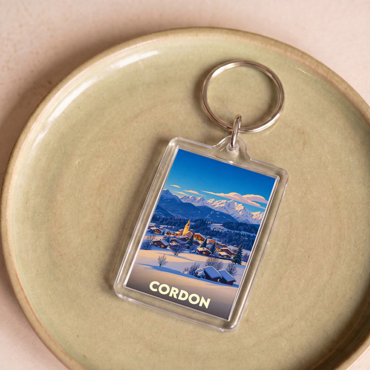 Porte-clés souvenir de la ville de Cordon avec une illustration stylisée d'un paysage de montagne enneigé.