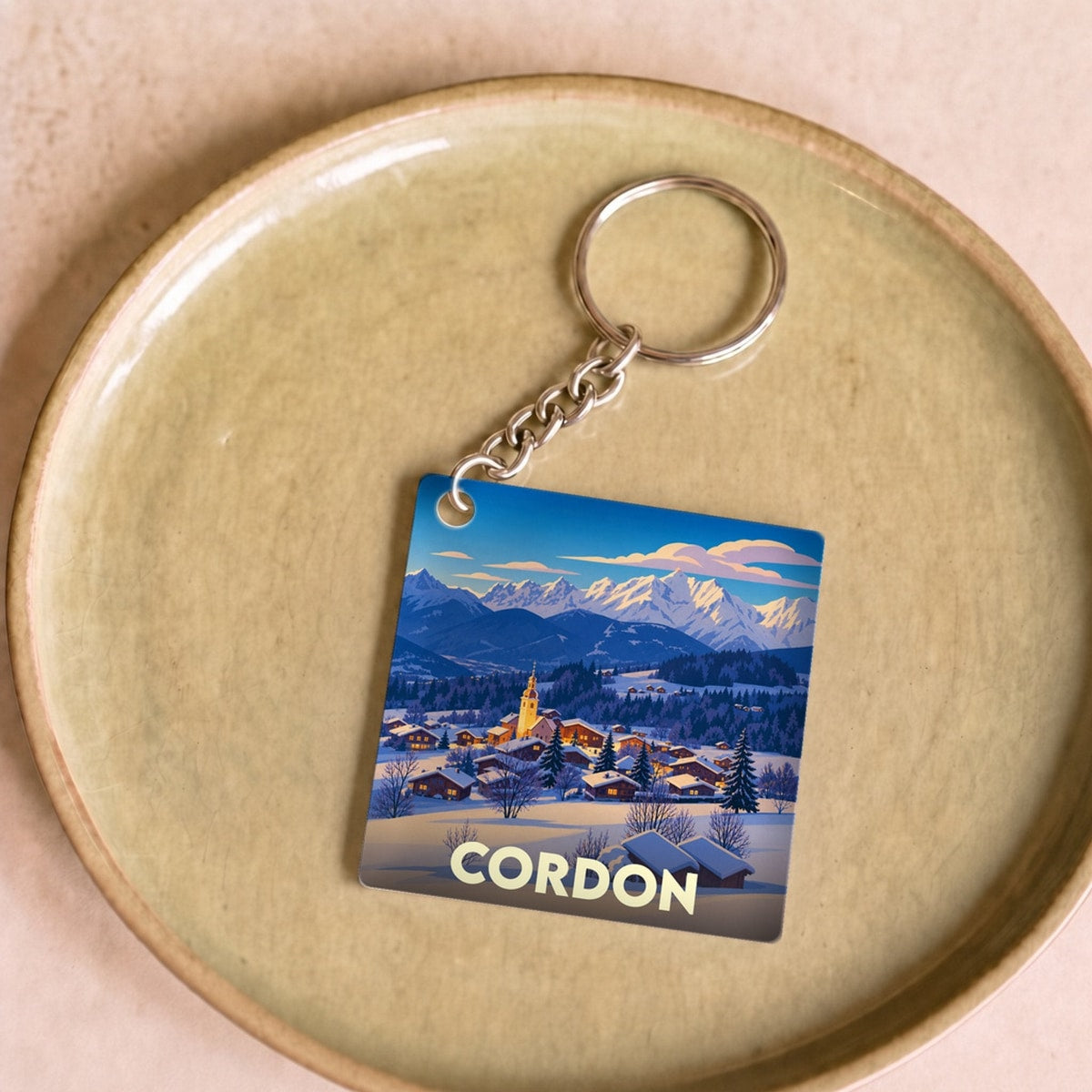 Porte-clés souvenir de la ville de Cordon avec une illustration stylisée d'un paysage de montagne enneigé.