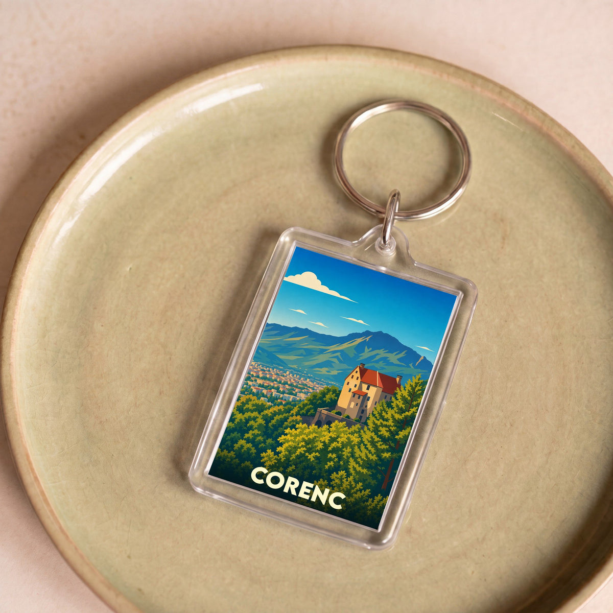 Porte-clés souvenir de la ville de Corenc avec une illustration stylisée d'un paysage montagneux.