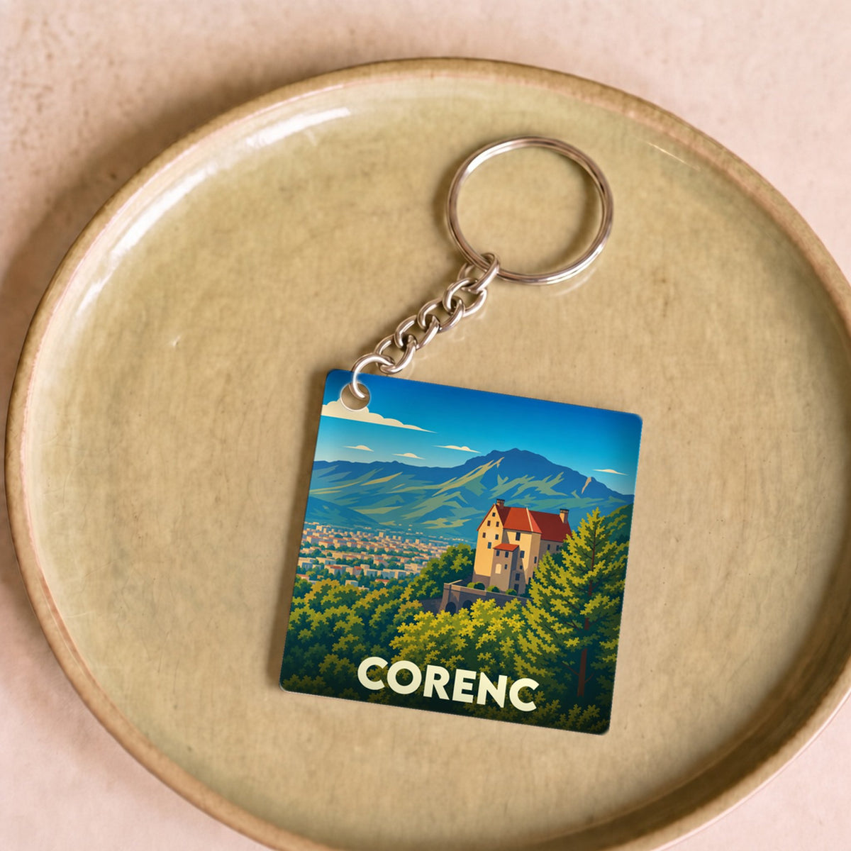Porte-clés souvenir de la ville de Corenc avec une illustration stylisée d'un paysage montagneux.