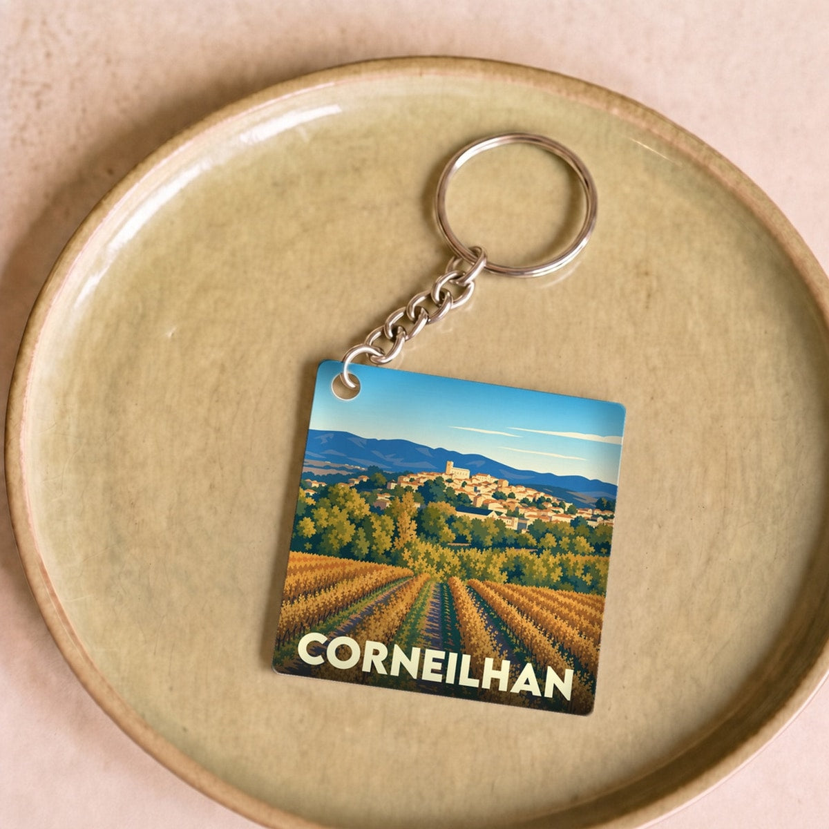 Porte-clés souvenir de la ville de Corneilhan avec une illustration stylisée de vignobles et du village.