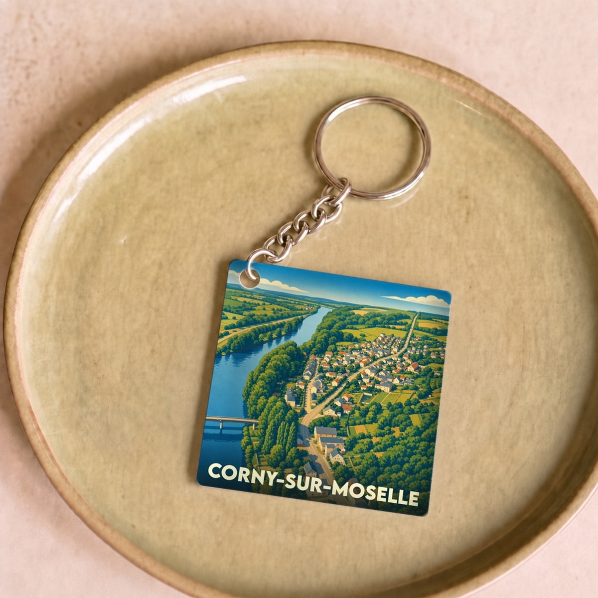 Porte-clés souvenir de Corny-sur-Moselle avec une illustration aérienne stylisée de la ville et de la Moselle.