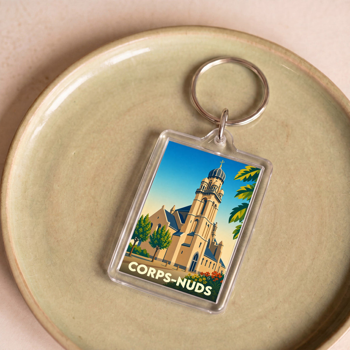Porte-clés souvenir de la ville de Corps-Nuds avec une illustration stylisée de son église.