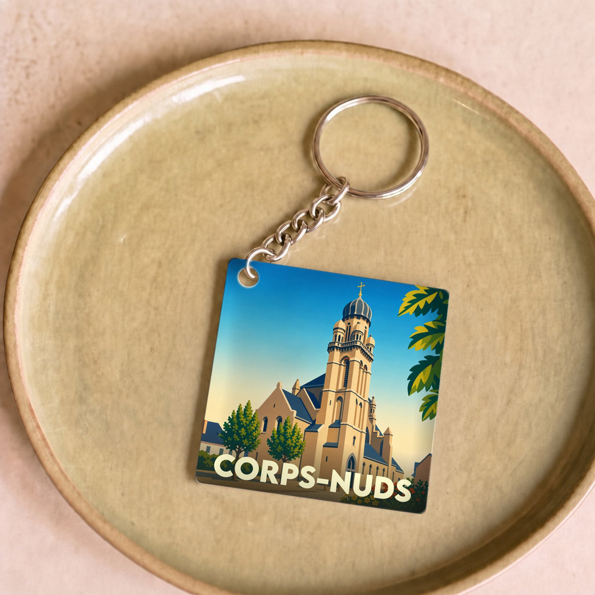 Porte-clés souvenir de la ville de Corps-Nuds avec une illustration stylisée de son église.