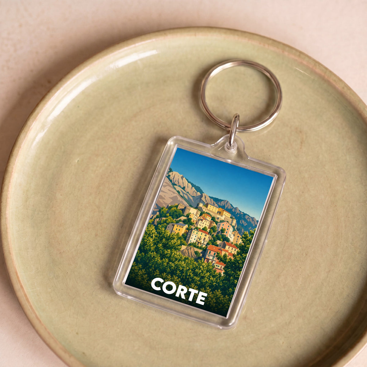 Porte-clés souvenir de la ville de Corte avec une illustration stylisée de ses maisons flanquées de montagnes.