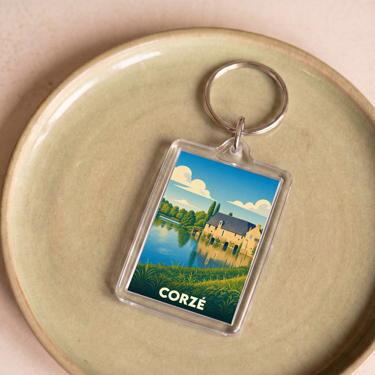Porte-clés souvenir de la ville de Corzé avec une illustration stylisée représentant un moulin au bord de l'eau.