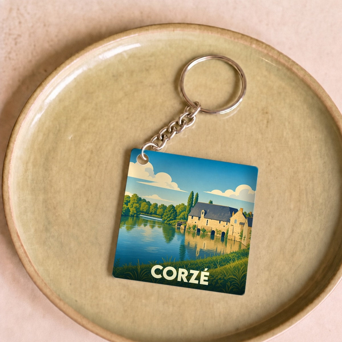 Porte-clés souvenir de la ville de Corzé avec une illustration stylisée représentant un moulin au bord de l'eau.