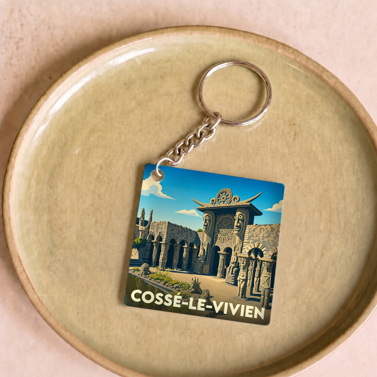Porte-clés souvenir de la ville de Cossé-le-Vivien avec une illustration stylisée du Musée Robert Tatin.