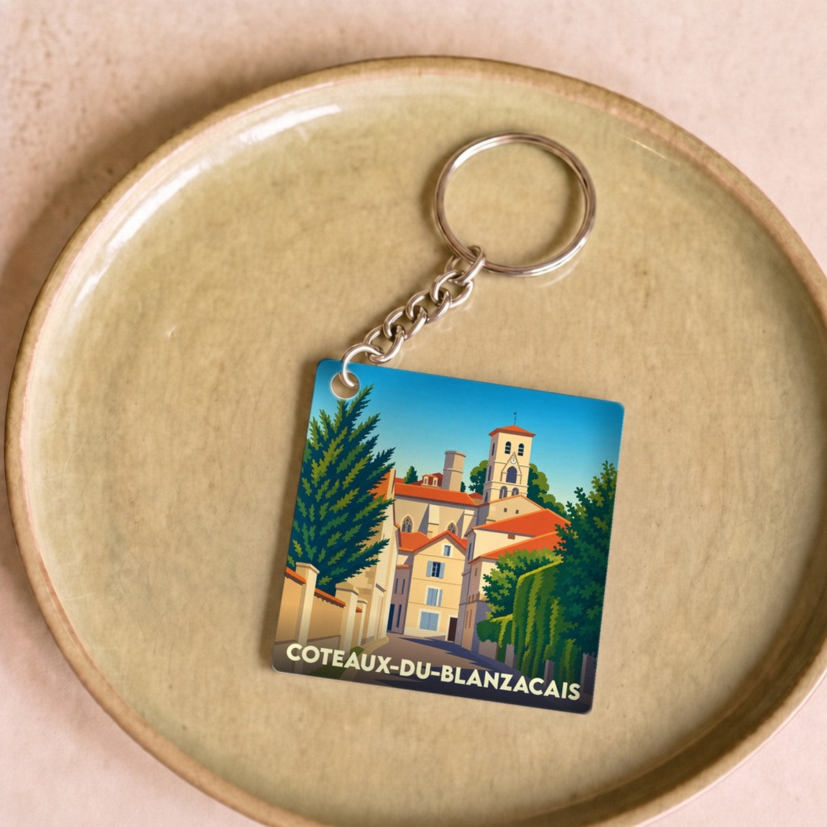 Porte-clés souvenir de la ville de Coteaux-du-Blanzacais avec une illustration stylisée.