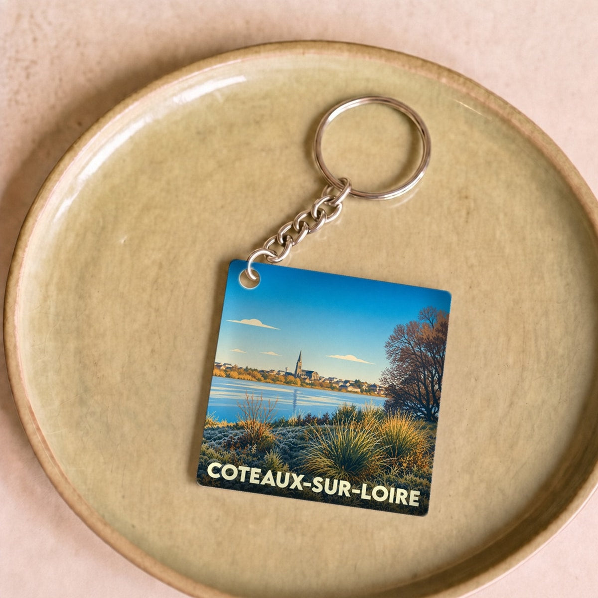 Porte-clés souvenir de la ville de Coteaux-sur-Loire avec une illustration stylisée d'un paysage de bord de Loire.