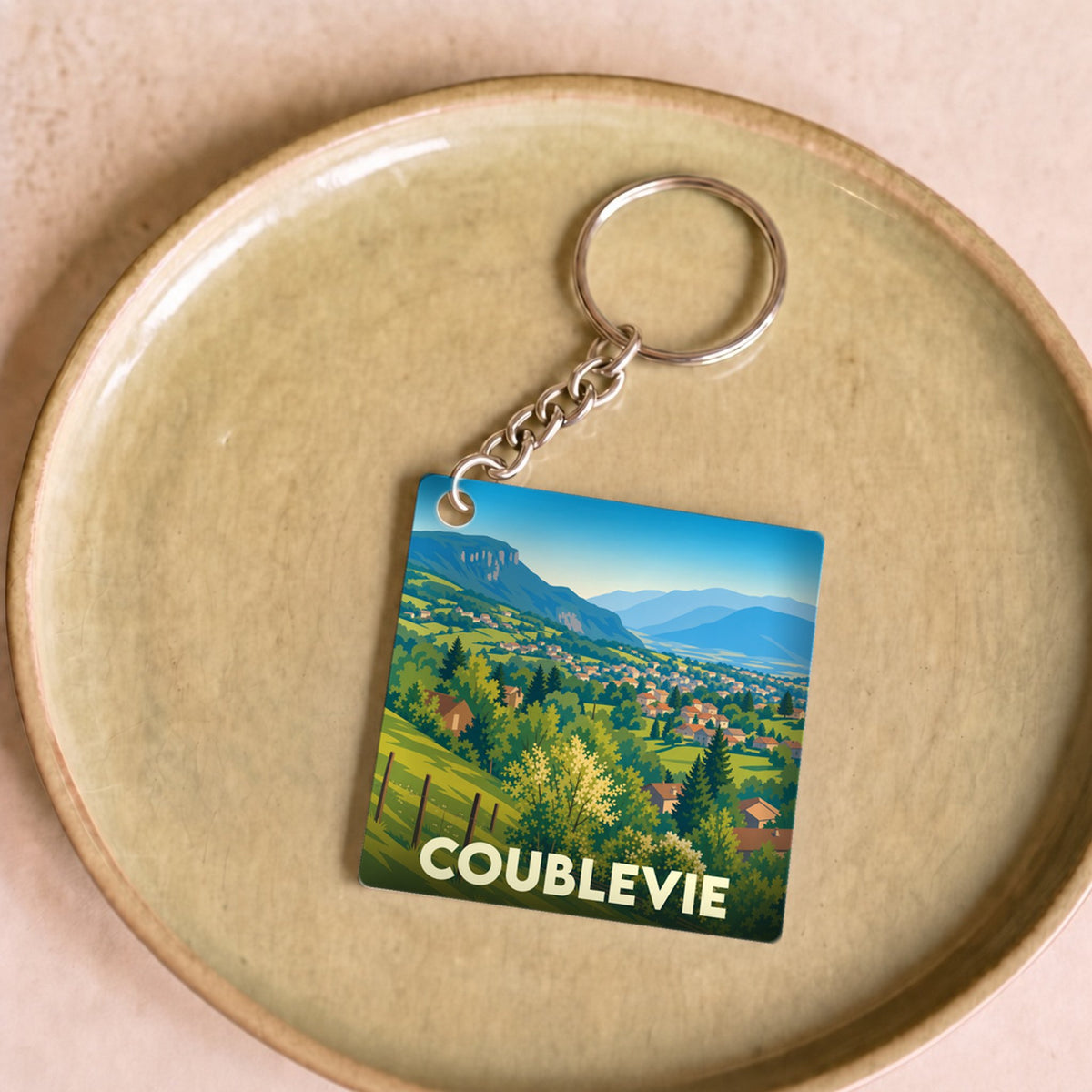Porte-clés souvenir de la ville de Coublevie avec une illustration paysagère stylisée.