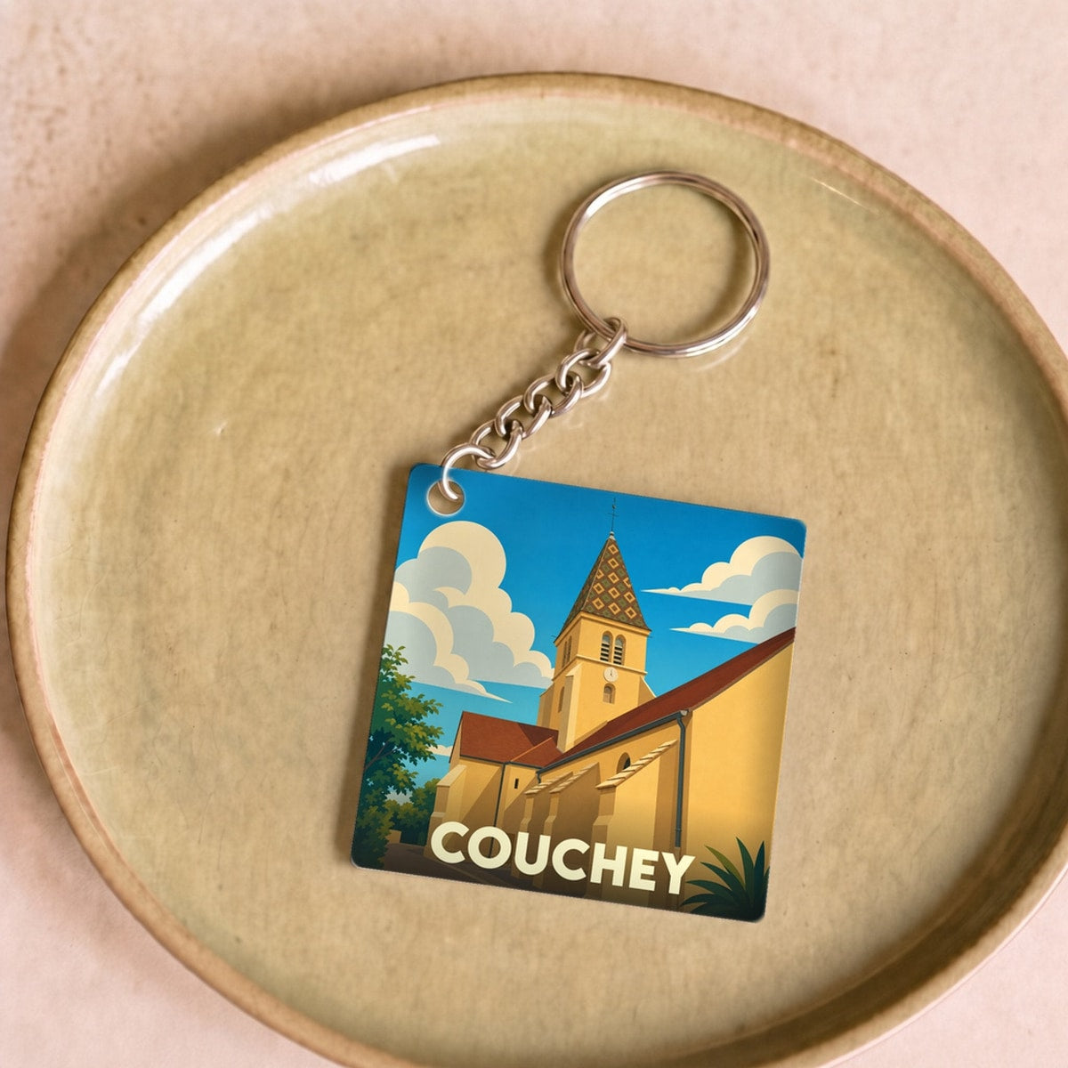 Porte-clés souvenir de la ville de Couchey avec une illustration stylisée de son église.
