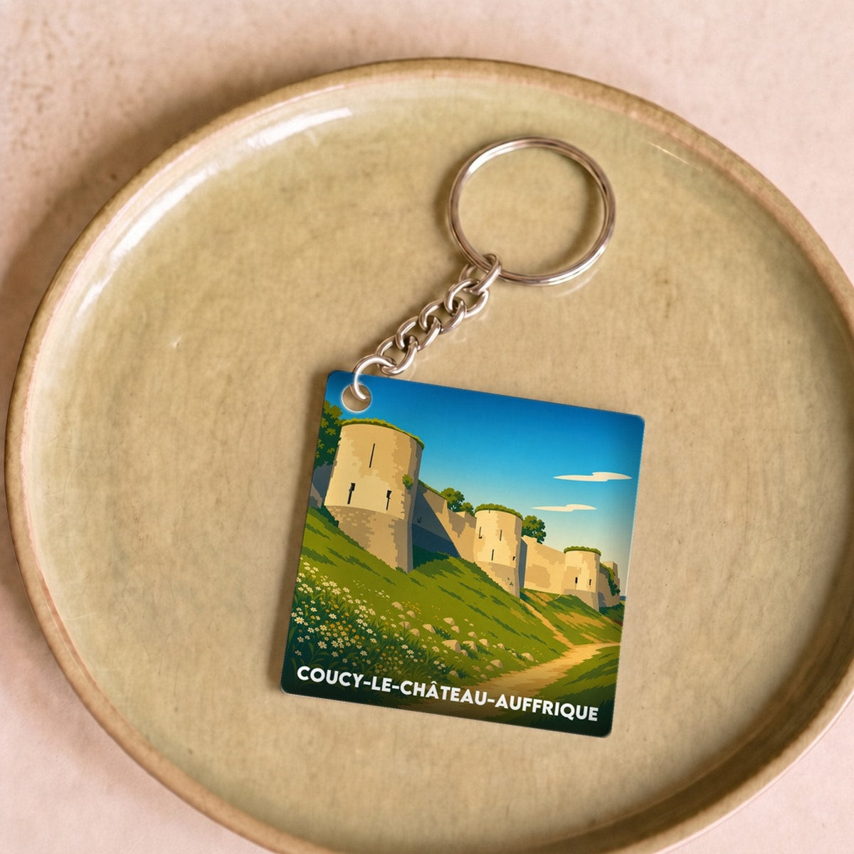 Porte-clés souvenir de la ville de Coucy-le-Château-Auffrique avec une illustration stylisée.