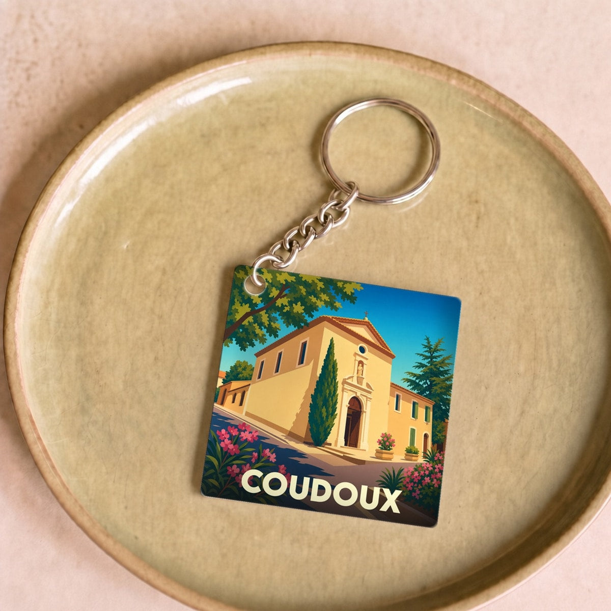 Porte-clés souvenir de la ville de Coudoux avec une illustration stylisée de son patrimoine.